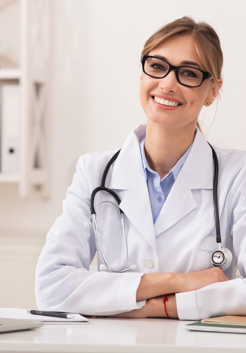 Lady Doctor Smiling At Camera Sitting In Modern Clinic Office